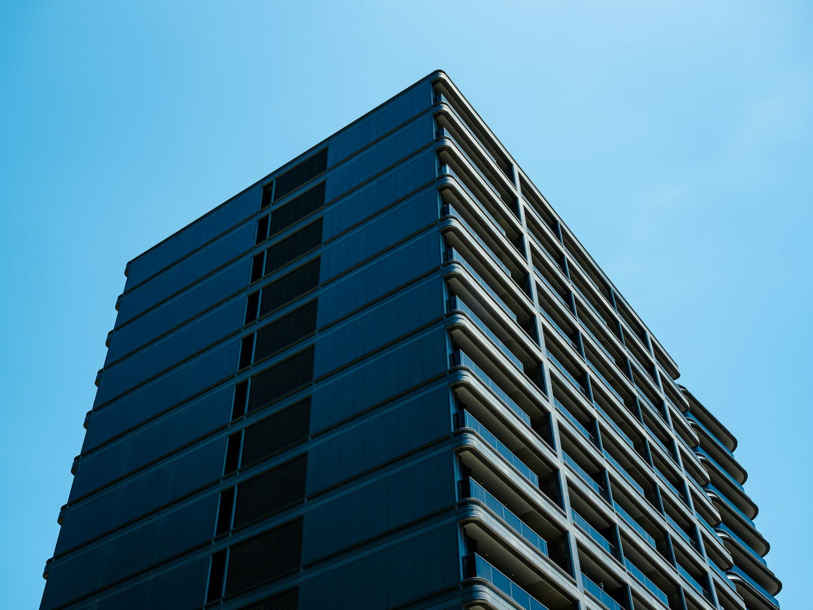 A modern glass office building against a clear sky